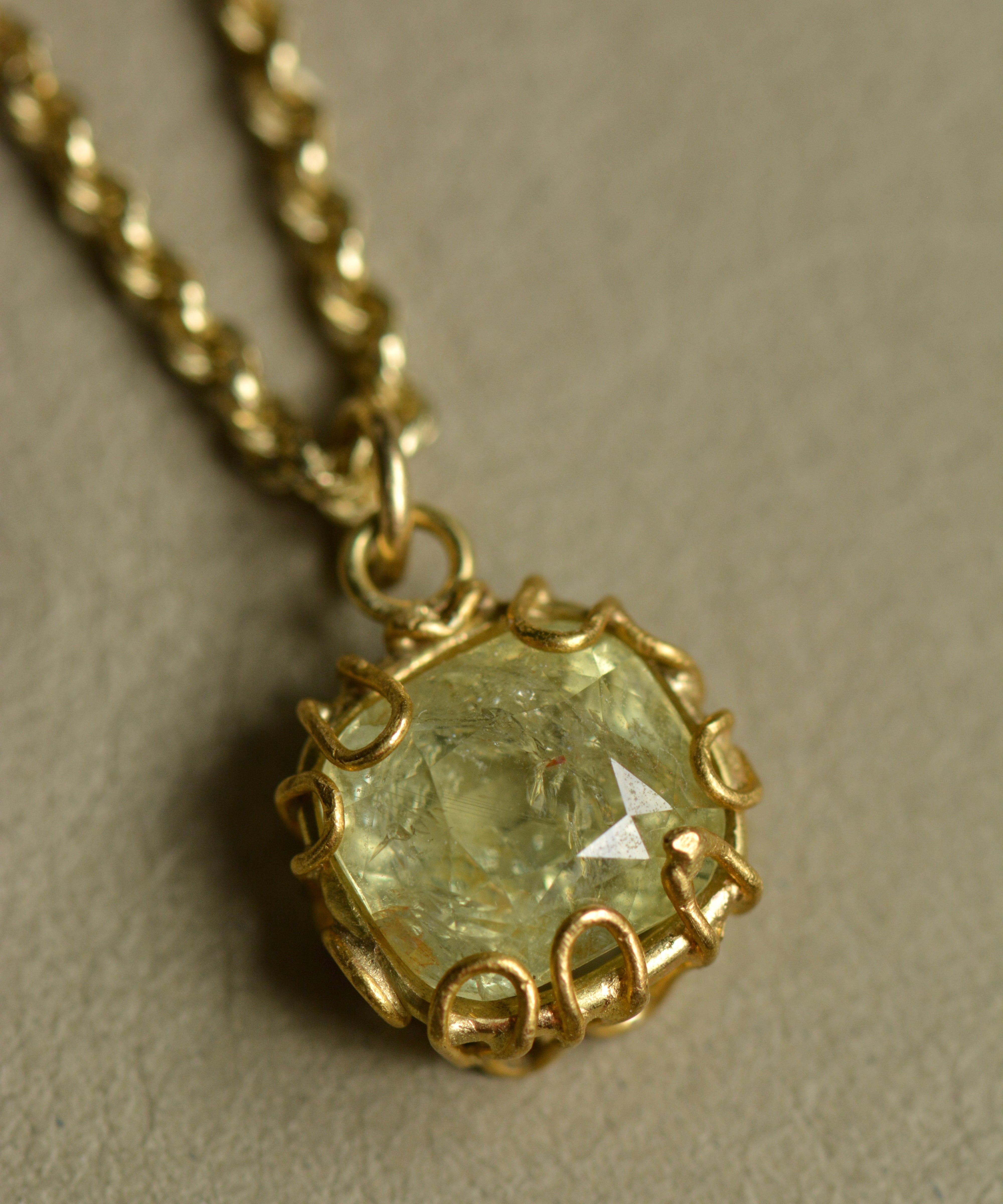 Tanzanian sapphire charm pendant in mellow pale green and yellow hues set in an organic 22k and 18k gold handcrafted setting.
