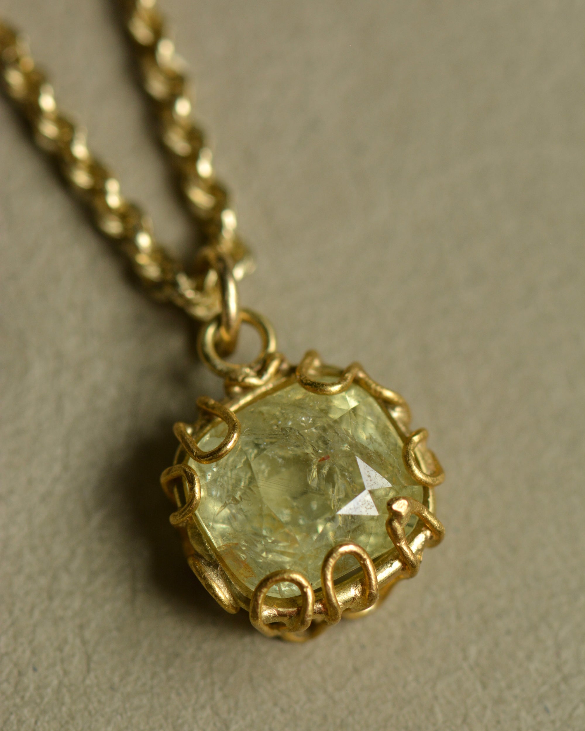 Tanzanian sapphire charm pendant in mellow pale green and yellow hues set in an organic 22k and 18k gold handcrafted setting.
