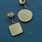 Reverse side of a pair of earrings in solid gold shows the hand signed details and post and butterfly closures.
