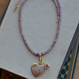 Malaya garnet beaded necklace styled with charms on book stack.