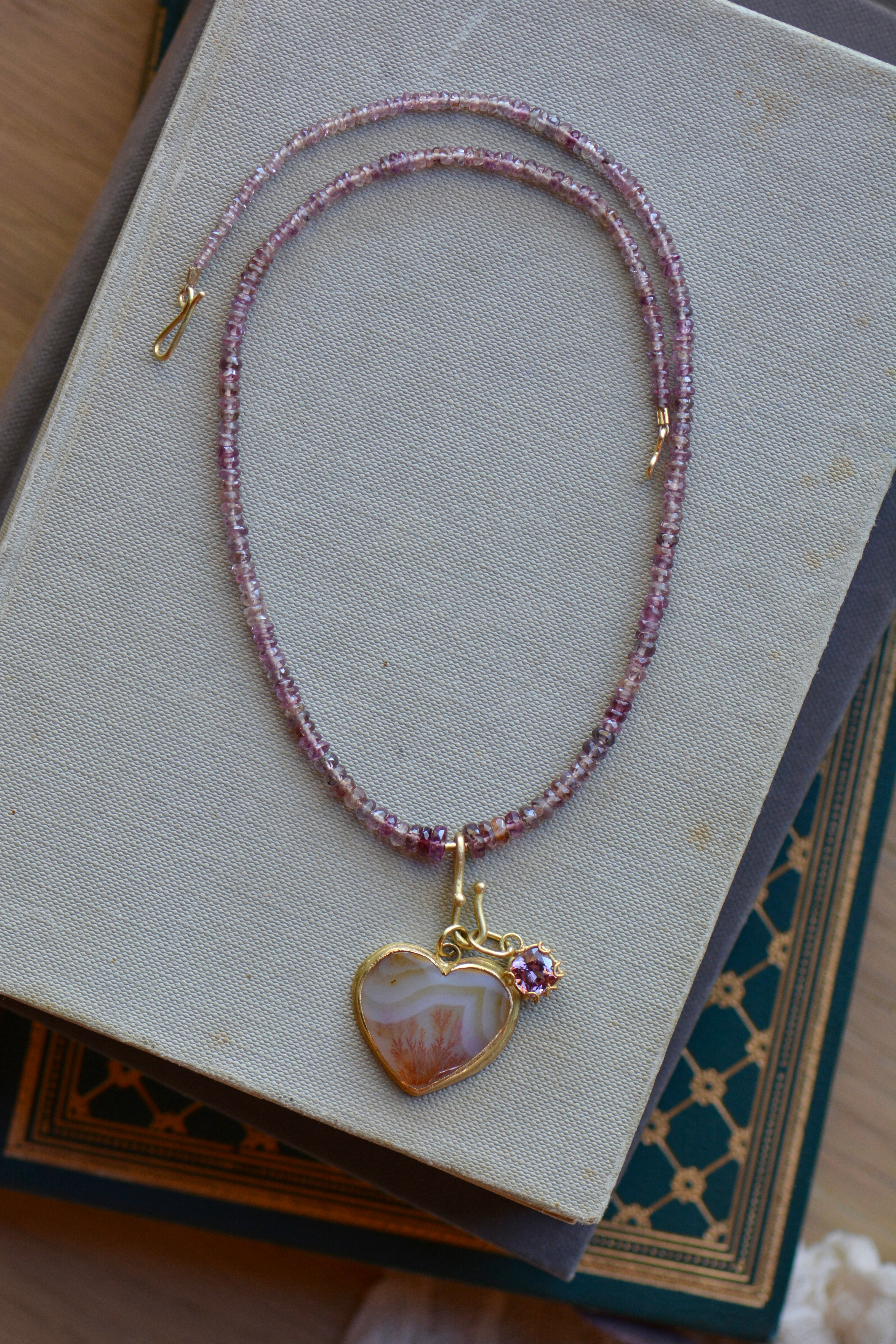 Malaya garnet beaded necklace styled with charms on book stack.
