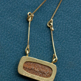 The reverse side of a necklace shows the gold setting cutout to reveal the brown textured back of the stone.