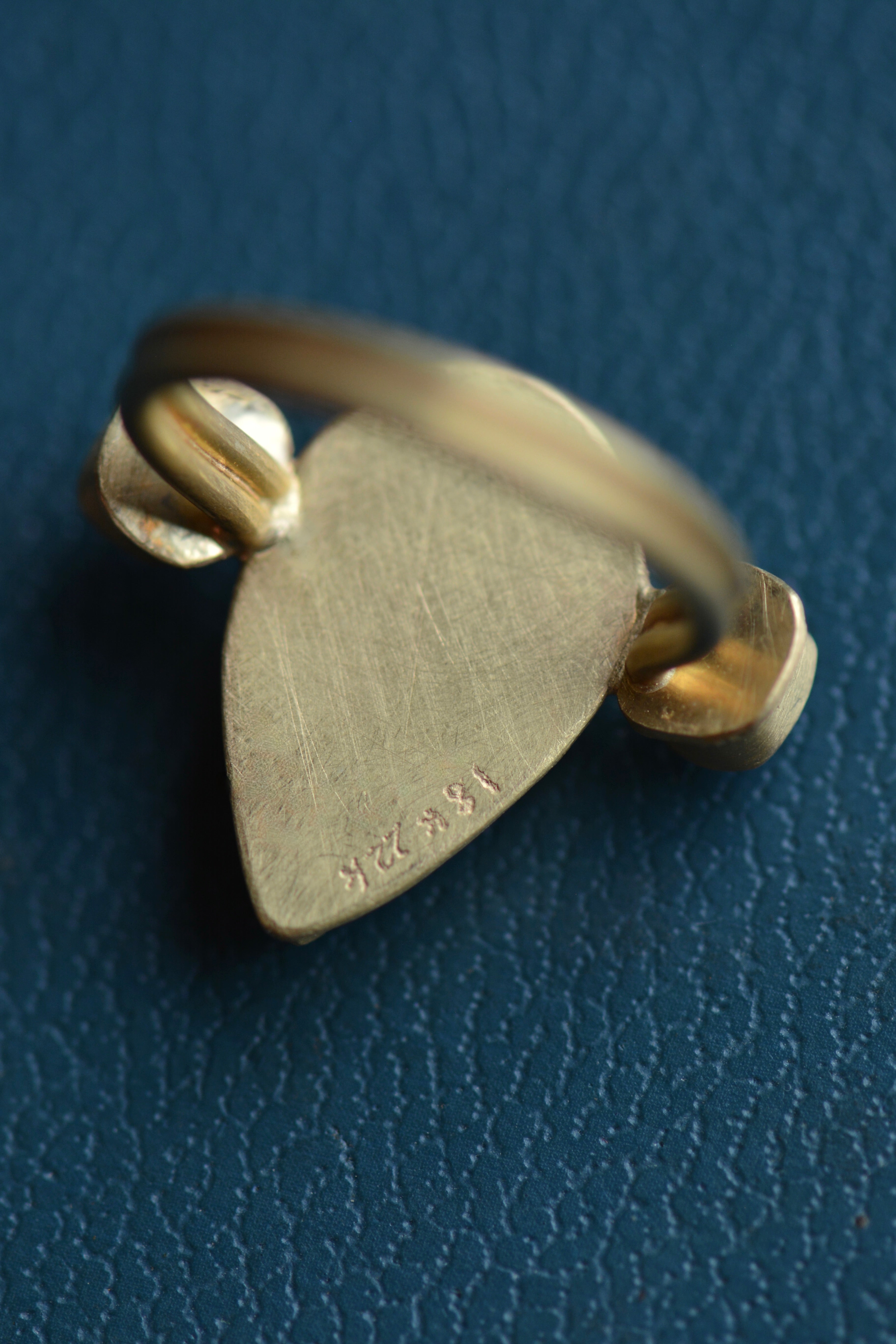 The reverse side of a cocktail ring is shown with solid gold backing and hand engraved hallmarks and signature.