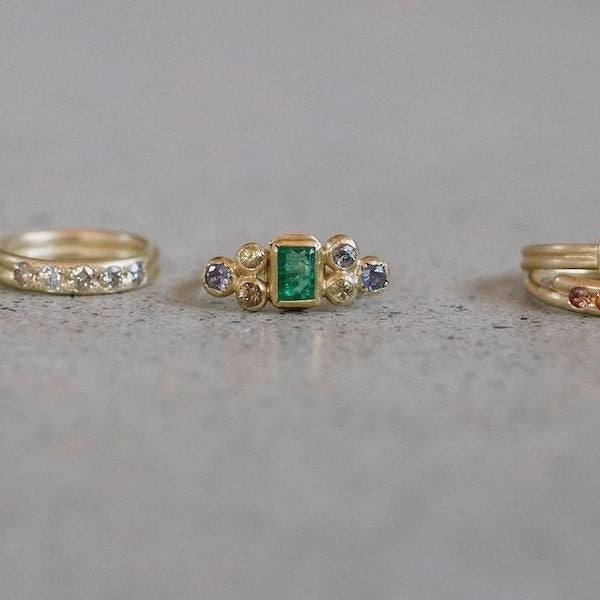 A row of gold rings with coloured gems on a stone ledge