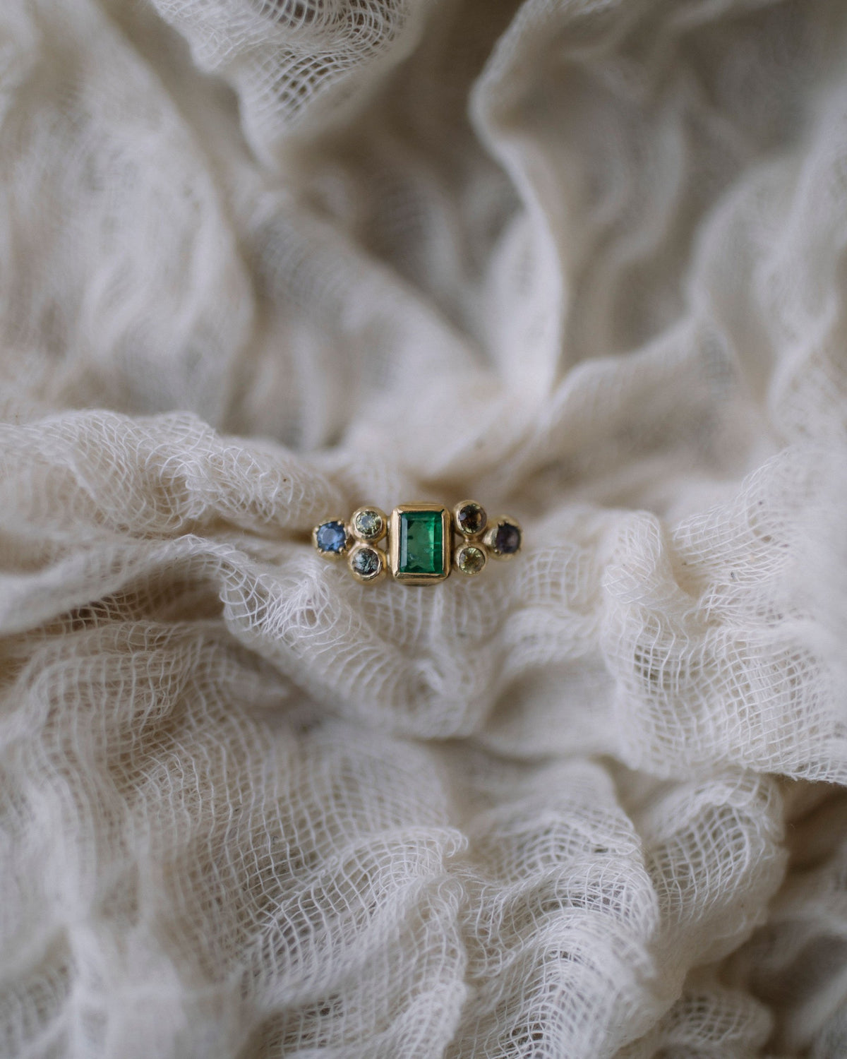 Emerald and gold ring on ivory muslin